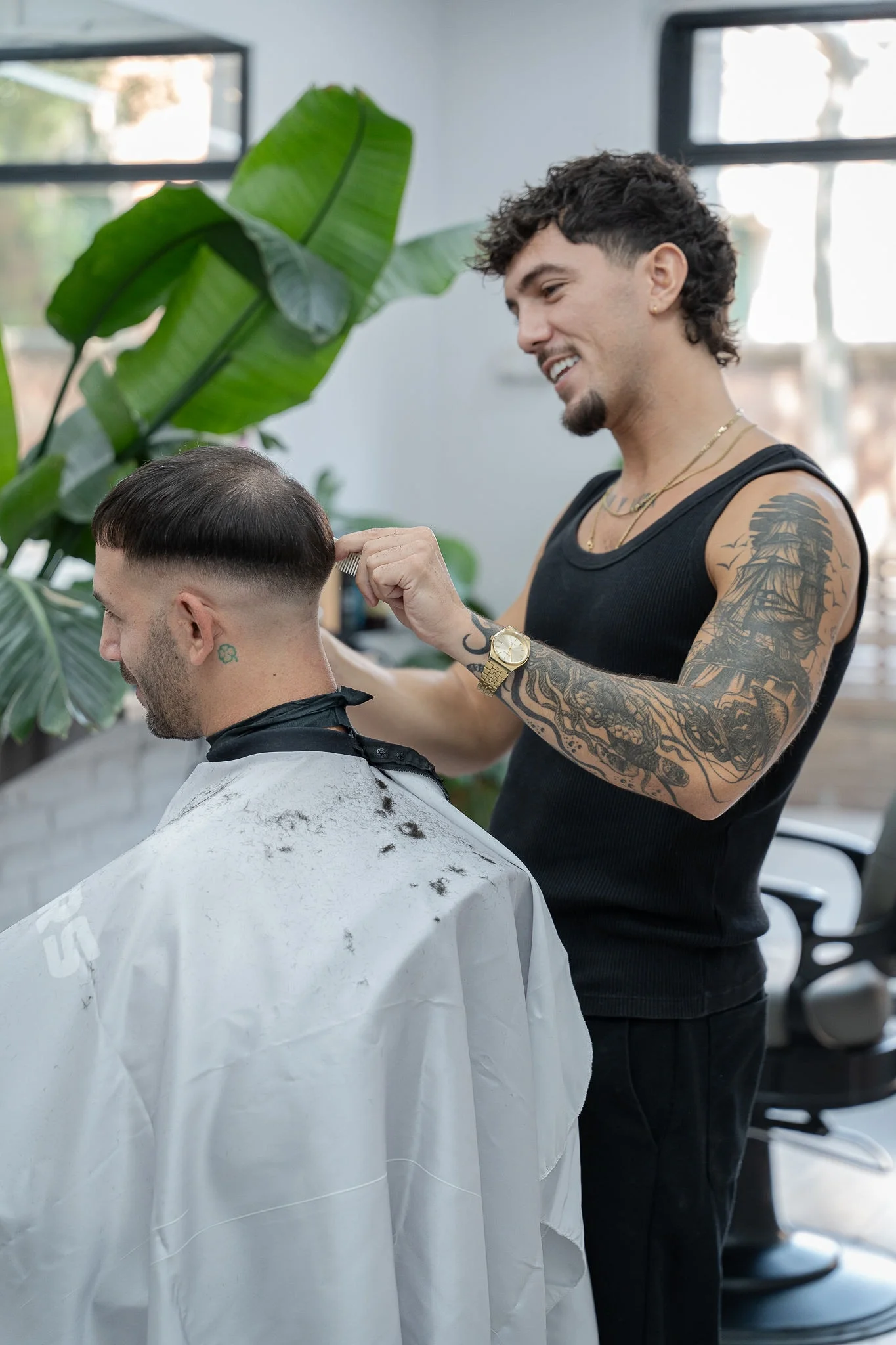 Barbero trabajando junto a las plantas y el ventanal del local